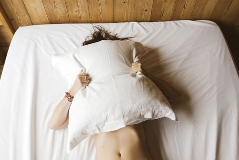 woman lying on bed covering her face with a pillow royalty free image 1588020516